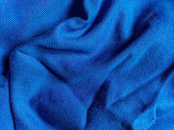 Background from blue fabric in folds. The texture of the fabric. blue fabric cloth background texture .