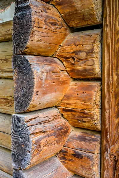 The corner of a house made of wooden logs, the corner joint of a chopped log house.Rustic log cabin wood building structure homestead historic site texture background .