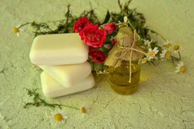 Arazide açık mavi ahşap masa üzerinde bir şişe papatya yağı ve sabun. Sabun, antiseptik, tıbbi papatya çiçekleri, hijyenik prosedürler için aromatik yağ.