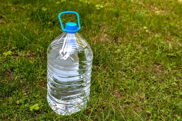 Large water bottle on grass in garden .Water bottle on green grass with copy space. plastic bottle with water on a background of green grass .