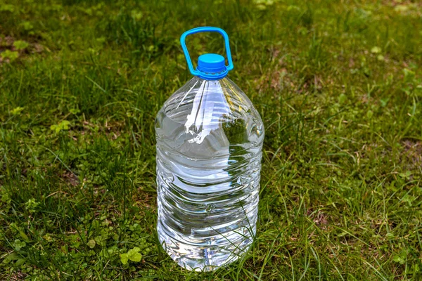 Large water bottle on grass in garden .Water bottle on green grass with copy space. plastic bottle with water on a background of green grass .