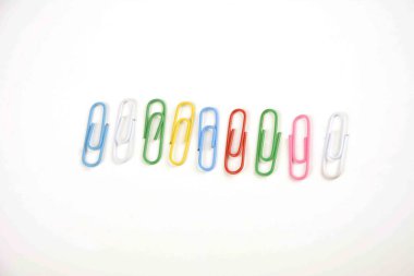 Çeşitli renkli kağıt klipler beyaz bir yüzey üzerinde yatıyor-bir arka plan beyaz bir taban ve renkli ataç oluşan