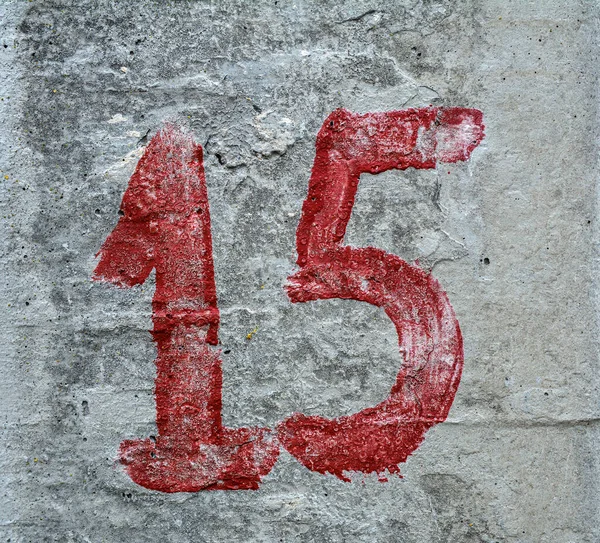 digits one and five painted on a worn concrete wall, number 15 centered