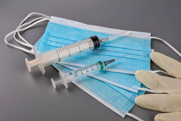 Used disposable medical face masks, latex gloves, syringes, test tubes on pastel blue background. Problem of environmental pollution during pandemic of coronavirus. COVID-19 waste. Top view, close up