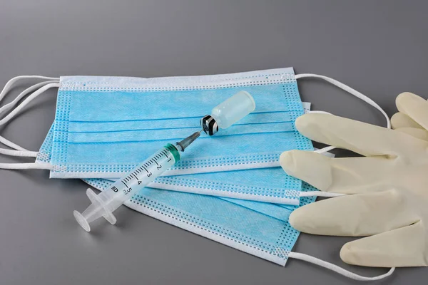 Used disposable medical face masks, latex gloves, syringes, test tubes on pastel blue background. Problem of environmental pollution during pandemic of coronavirus. COVID-19 waste. Top view, close up