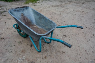 Garden tools rakes trolley summer spring .one black wheel on a green metal garden wheelbarrow .