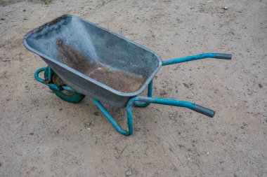 Garden tools rakes trolley summer spring .one black wheel on a green metal garden wheelbarrow .