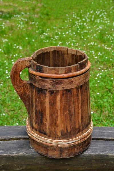 old and cracked wooden buckets traditional water container .wooden bucket old and weathered with a handle stands on the grass close-up