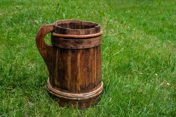 old and cracked wooden buckets traditional water container .wooden bucket old and weathered with a handle stands on the grass close-up