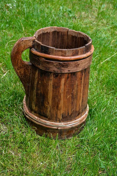 old and cracked wooden buckets traditional water container .wooden bucket old and weathered with a handle stands on the grass close-up