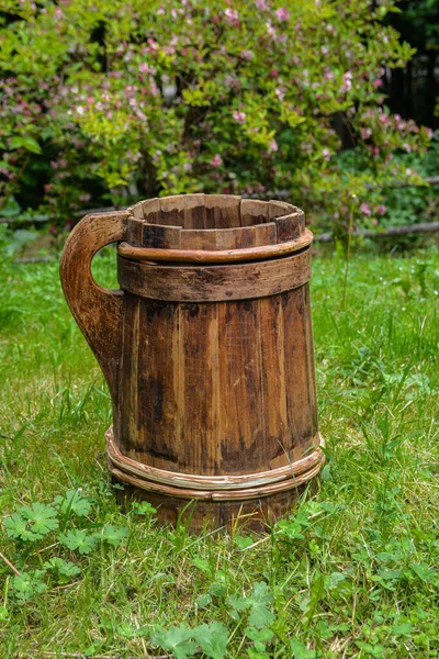 old and cracked wooden buckets traditional water container .wooden bucket old and weathered with a handle stands on the grass close-up