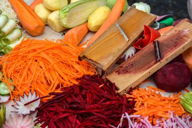 Sebzeleri pişirmeye hazır et. Tahta kesim tahtasının üzerinde gökkuşağı renginde sebzeler kes. .