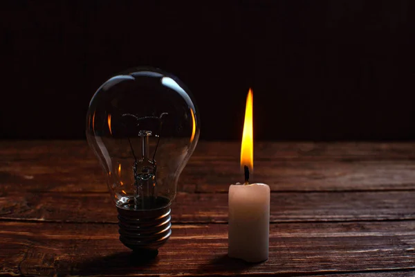 candle light shine on incandescent bulb, no electricity makes electrical equipment useless .global energy crisis.