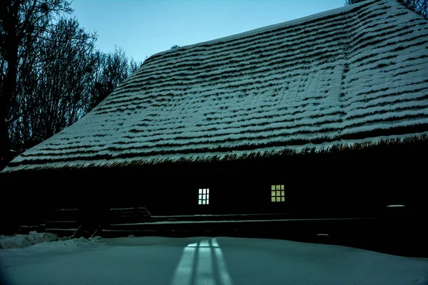 Romantic view of old traditional wooden forest cabin in the woods embedded in scenic northern winter wonderland scenery in beautiful mystic twilight during blue hour at dusk .