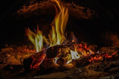 Evin şöminesinde yanan ahşap odunları kaplayan alevlerin yakın plan görüntüsü. .
