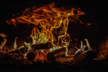 Evin şöminesinde yanan ahşap odunları kaplayan alevlerin yakın plan görüntüsü. .