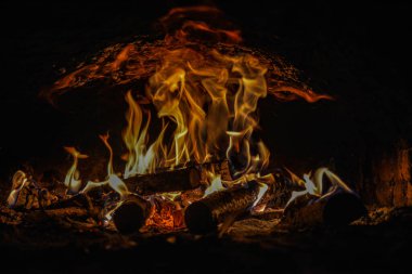 Evin şöminesinde yanan ahşap odunları kaplayan alevlerin yakın plan görüntüsü. .