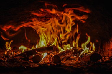 Evin şöminesinde yanan ahşap odunları kaplayan alevlerin yakın plan görüntüsü. .