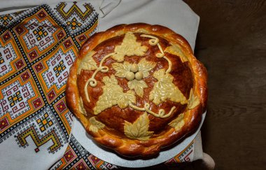 Beyaz havluyla geleneksel geleneksel düğün ekmeği. Masanın üzerinde işlenmiş havlunun yanında duran tuzlu taze Ukrayna somunu..