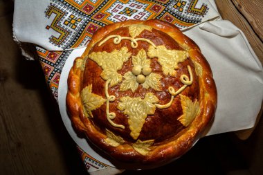 Beyaz havluyla geleneksel geleneksel düğün ekmeği. Masanın üzerinde işlenmiş havlunun yanında duran tuzlu taze Ukrayna somunu..