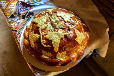 Beyaz havluyla geleneksel geleneksel düğün ekmeği. Masanın üzerinde işlenmiş havlunun yanında duran tuzlu taze Ukrayna somunu..