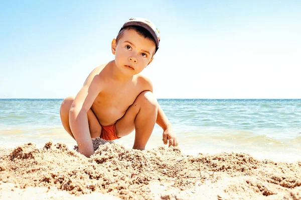 Gün batımında küçük bir çocuk bir göletin yanında kumsalda oynar. Kumdan evler inşa eder ve onları yok eder. Tatilde çocuklarla tatil kavramı..