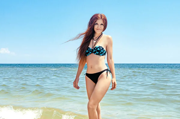 Beach bikini woman carefree running in freedom fun. Joyful happy Ukrainian redhead girl relaxing showing joy and happiness in slim body for weight loss diet concept on perfect white sand.