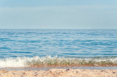 Bu fotoğraf, rahatlatıcı hava sahnesini, yaz tatili şablonu afişini tasvir ediyor. Dalgalar inanılmaz mavi okyanus gölü, deniz kıyısı, kıyı şeridi ile sörf yapar. Huzurlu, parlak sahil, deniz kenarı.