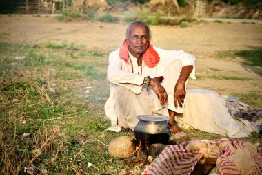 Davangere, Karnataka, Hindistan - 29 Ocak 2021: Hintli fakir bir köyün portresi yol kenarındaki bir alüminyum taklada şenlik ateşinde pişiyor.