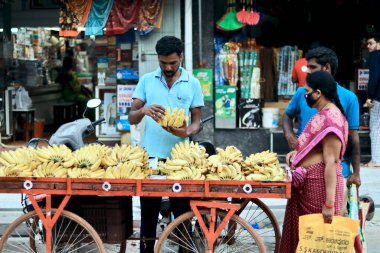 Davangere, Karnataka, Hindistan - 15 Aralık 2021: Hintli bir muz tüccarı elinde arabasıyla sokakta muz satıyor..
