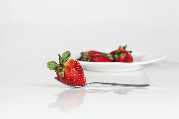 Strawberries with spoon in a plate — Stock Photo, Image