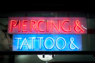 Neon signboard with Piercing & Tattoo at night. clipart