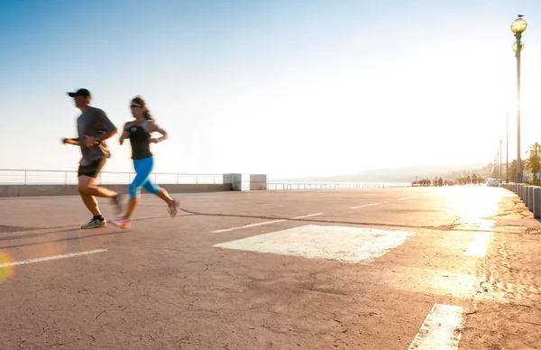 Man and woman running at the seaside. — Stock Photo, Image