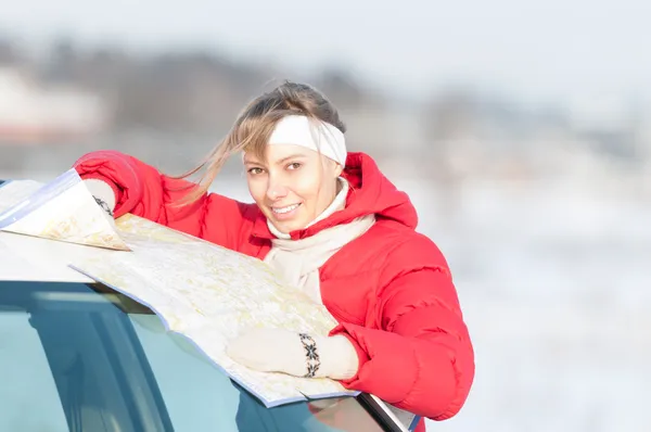 Mulher bonita perto de carro segurando mapa no inverno . — Fotografia de Stock