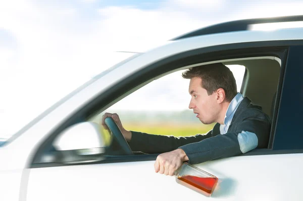 Drunk man driving car with bottle in hand. — Stock Photo, Image