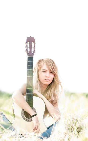 Beautiful woman with guitar sitting on grass. — Stock Photo, Image