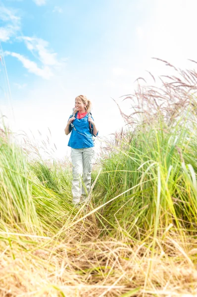 Jeune fille marche dans la prairie avec sac à dos sur . — Photo