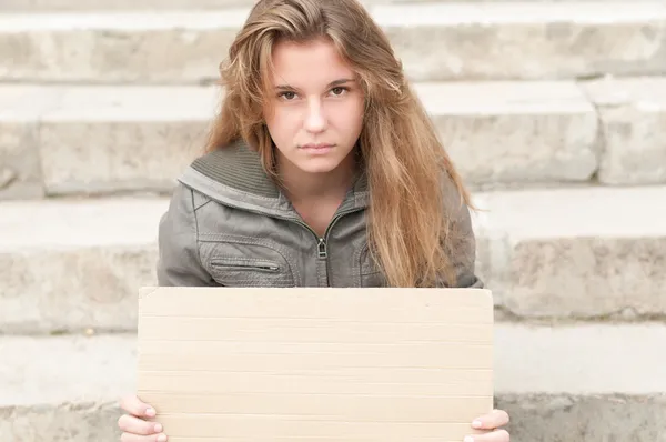 Menina triste jovem ao ar livre com sinal de papelão em branco . — Fotografia de Stock