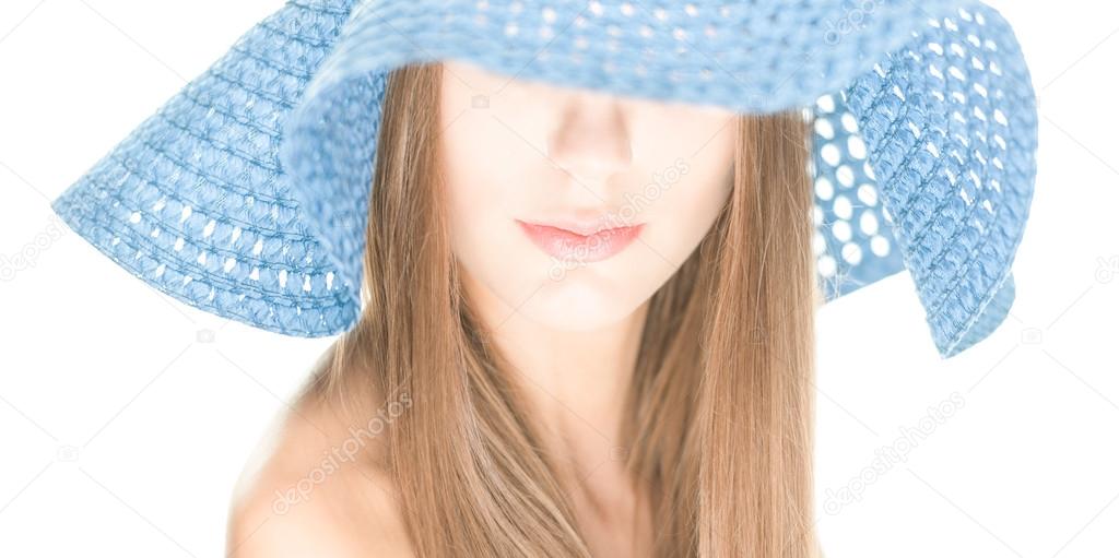 Young woman with half hidden face under blue hat.