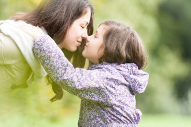 Mother and daughter looking at each other in park. clipart