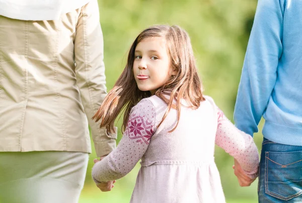 Meisje tong tonen tijdens het wandelen met ouders. — Stockfoto