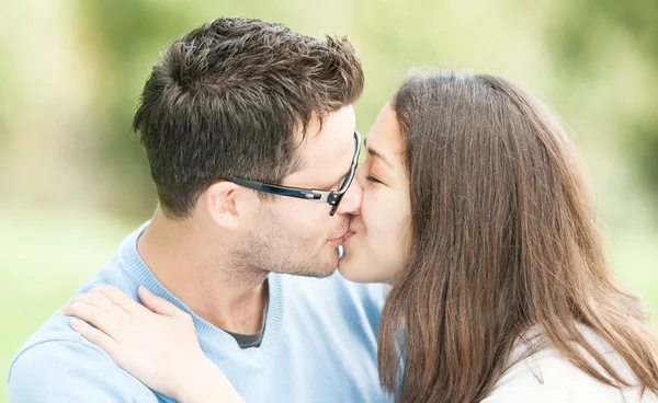 Ładna kobieta i mężczyzna w okularach pocałunki w parku. — Zdjęcie stockowe