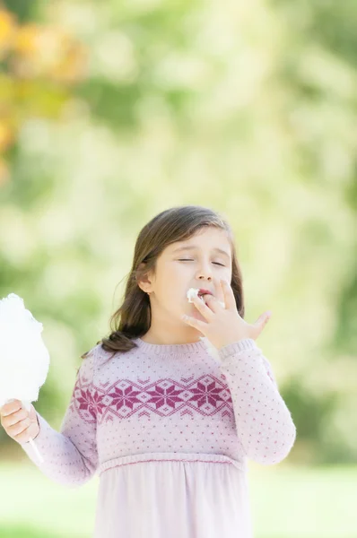 Mooi meisje suikerspin eten in park. — Stockfoto