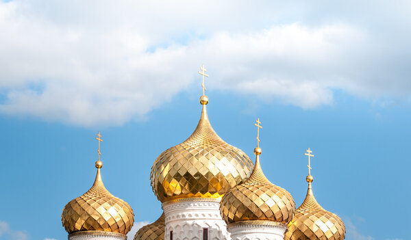 Golden domes of russian church against blue sky.