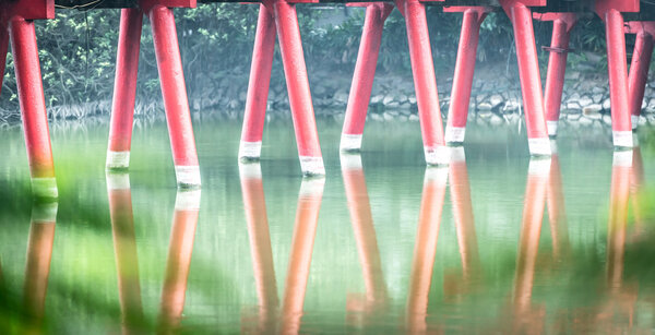 Detail of wooden red bridge with water background.
