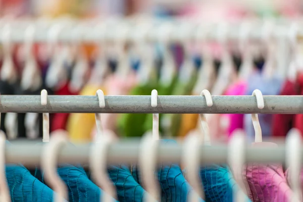 Rijen van kleurrijke kleding op hangers bij shop. — Stockfoto