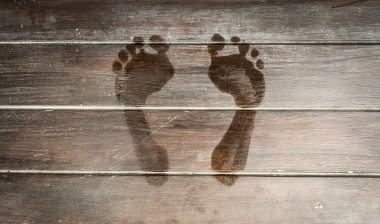 Wet footprints on dark wooden plank floor. clipart