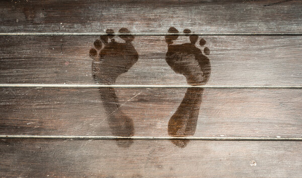 Wet footprints on dark wooden plank floor.