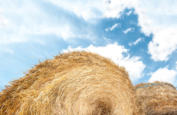 Haystack outdoors, sky with clouds in background.