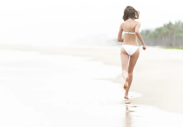 Woman running on wet sand — Stock Photo, Image